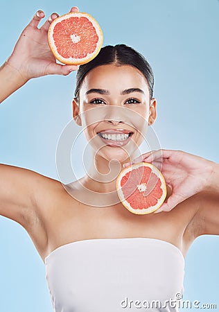 Wellness, health and beauty with woman and grapefruit with a smile against a blue background studio. Skincare, nutrition Stock Photo