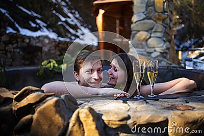 Couple Relaxing with champagne In Hot Tub Jacuzzi Outdoor. Honeymoon Couple Relaxing Together. Stock Photo