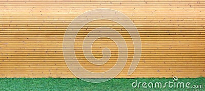 Wellow wooden wall from horizontal planks and green yard lawn background Stock Photo