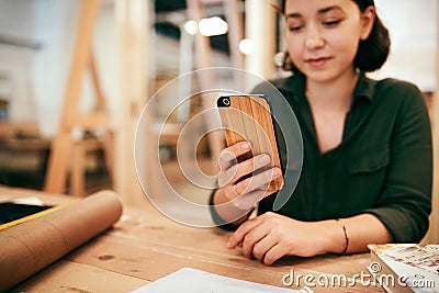 Were getting so many orders for our new phone covers. a female carpenter using her cellphone while sitting in her Stock Photo