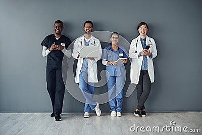 Were here so you can face another day. a group of doctors standing against a grey background at work. Stock Photo