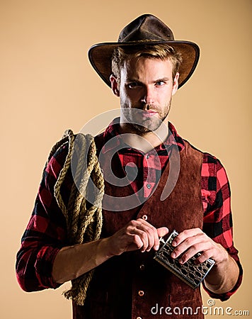 Western life. Sheriff concept. Bourbon whiskey. Western culture. Man wearing hat hold rope and flask. Lasso tool Stock Photo