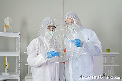 Western scientists couple using hologram tablet with copy space to develop vaccine of covid-19 virus in lab or laboratory in Stock Photo