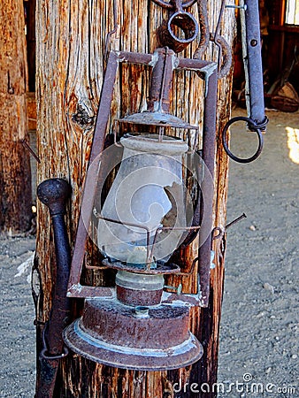 Western style rusty antique broken oil lantern hanging at farm countryside old lamp vintage style hang on wood background. Stock Photo