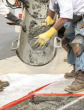 Wet cement off loaded by construction workers from a cement truck chute into a concrete form with rebar Stock Photo