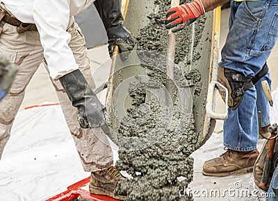 Wet cement off loaded by construction workers using a shovel from a cement truck chute into a concrete form Stock Photo