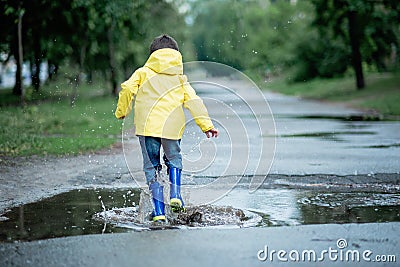 A wet child is jumping in a puddle. Fun on the street. Tempering in summer Stock Photo