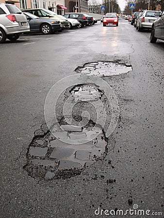 Wet city street with potholes Stock Photo