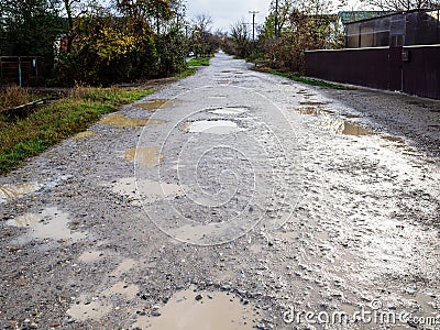 wet dirty gravel road with puddles in village Stock Photo