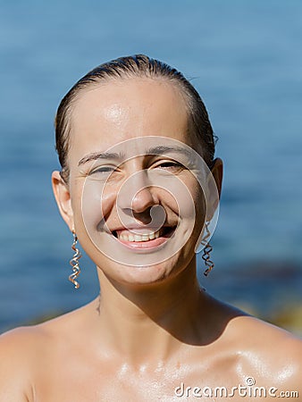 Wet girl poses smiling and squinting from the sun Stock Photo