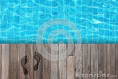 Wet human footprint on wooden floor beside blue water in swimming pool at outside buildings from top view. Stock Photo