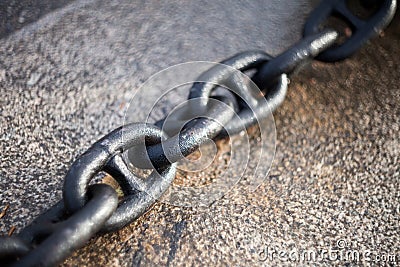 Wet links of a heavy anchor carabable iron chain lying on a granite slab with blurred background Stock Photo