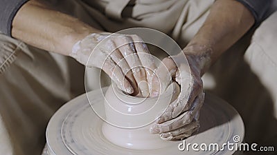 Wet male potter& x27;s hands sculpting soft clay and shaping the pot on potters wheel. Master gives shape to the pottery Stock Photo