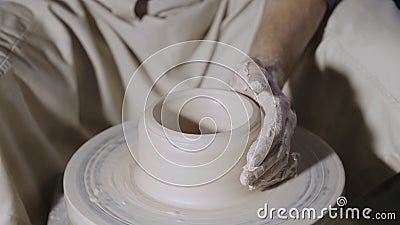 Wet male potter& x27;s hands sculpting soft clay and shaping the pot on potters wheel. Master gives shape to the pottery Stock Photo