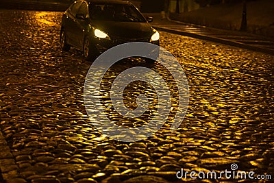 Wet night golden color pavement in the light of a passing car Stock Photo