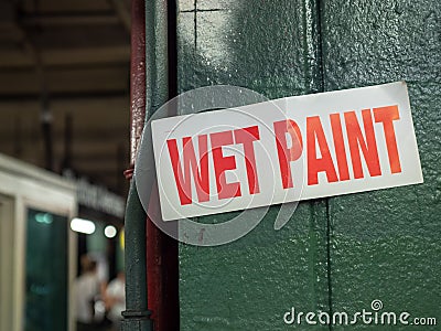 Wet paint sign hanging on green pillar in underground subway location Stock Photo