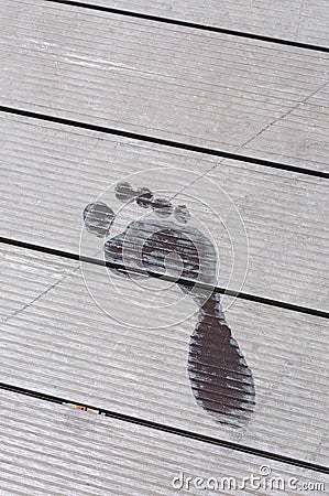 Wet print of a human foot upon the wooden floor near a pool Stock Photo