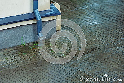 Wet sidewalk and roadway in the city after the rain. Water splashes on the road during a downpour. Large raindrops on the surface Stock Photo