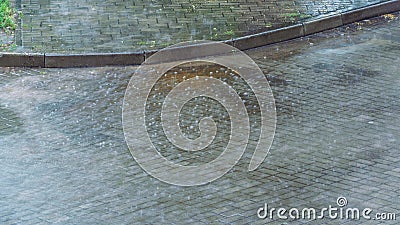 Wet sidewalk and roadway in the city after the rain. Water splashes on the road during a downpour. Large raindrops on the surface Stock Photo