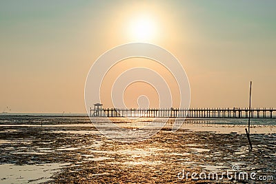 Wetland after low tide sea with silhouette pier over sunset sky Stock Photo