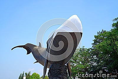 A whale statue in a park wears a mask as a symbol of COVID prevention Editorial Stock Photo