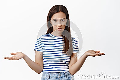 So what. Annoyed confused woman stare upset at camera, spread hands sideways and shrugging shoulders, dont understand Stock Photo