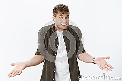 So what chill and relax. Unbothered careless fair-haired guy shrugging with hands raised in confusion and dismay smiling Stock Photo