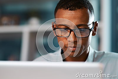 This is what I call minding your own business. a handsome young businessman working on his laptop during a late night Stock Photo