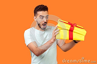 What`s in the box. Portrait of curious man looking inside gift box. indoor studio shot isolated on orange background Stock Photo