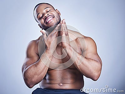 So this is what success feels like. Studio shot of a handsome young man feeling his skin against a blue background. Stock Photo