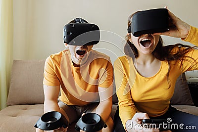 What to do at home. A guy and a girl play virtual games. People are wearing virtual reality helmets for game. Stock Photo