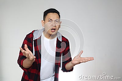 What you do that? Portrait of confused annoyed man shrug raising arms, asking and having no idea what happening. over grey Stock Photo