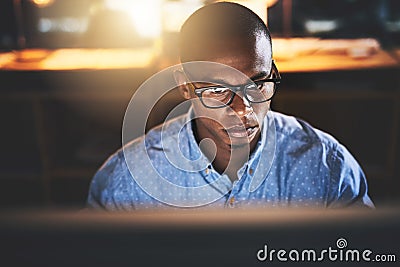 This is what you do when youre passionate about success. a handsome young businessman using a computer during a late Stock Photo