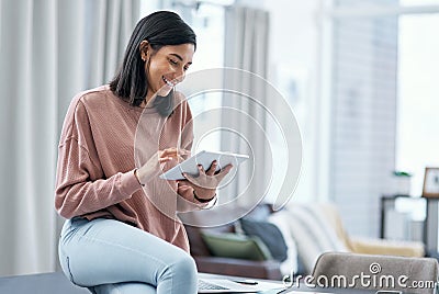 Whatever your work, do it like a boss. a confident young woman using a digital tablet while working from home. Stock Photo