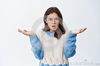 Whats wrong. Confused annoyed girl dont understand, shrugging shoulders with hands spread sideways and puzzled face Stock Photo