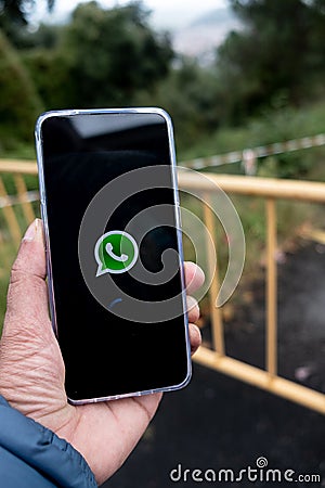 Hand holding mobile phone with WhatsApp logo on the screen Editorial Stock Photo