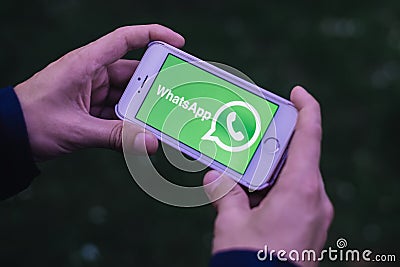 BERLIN, GERMANY - MAY 30, 2018: Closeup of hands holding iPhone screen with WHATSAPP MESSENGER LOGO and ICON Editorial Stock Photo