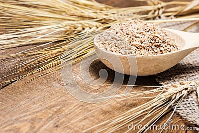 Wheat bran in wooden spoon with wheat ears Stock Photo