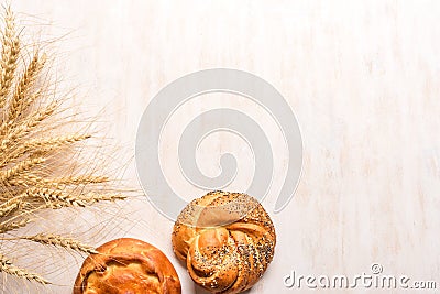 Wheat ears and fresh buns on white wooden background Stock Photo