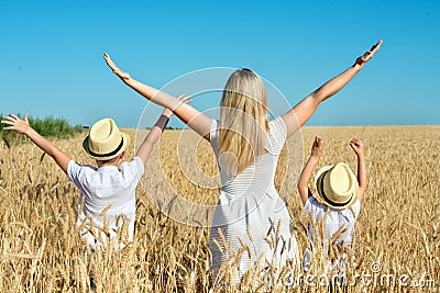Mother and two sons stand looking at the wheat harvest. Stock Photo