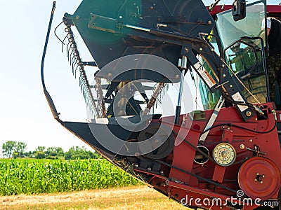 Wheat harvesting in the summer. Red harvester working in the field. Golden ripe wheat harvest agricultural machine harvester on Editorial Stock Photo