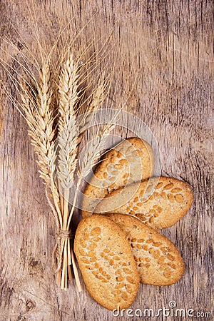 Wheat spikes and cereal biscuits on an old wooden background Stock Photo