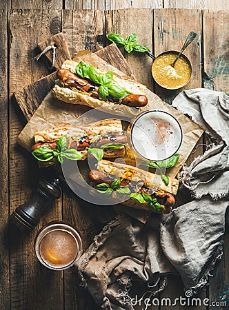 Wheat unfiltered beer and grilled sausage dogs in baguette Stock Photo