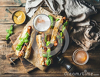 Wheat unfiltered beer and grilled sausage dogs in baguette Stock Photo