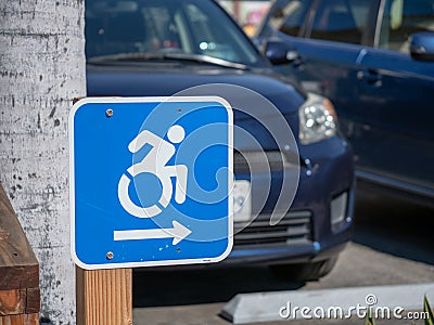 Wheel chair traffic sign pointing to the right in a parking lot Stock Photo