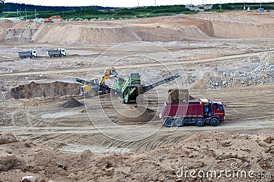 Wheel front-end loader loads sand into a dump truck. Heavy machinery in the mining quarry, excavators and trucks. Stock Photo