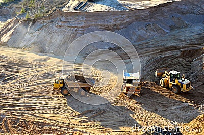 Wheel front-end loader unloading sand into heavy dump truck at the opencast quarry Stock Photo