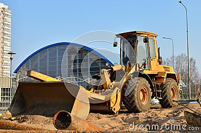 Wheel loader with a bucket on a street in the city during the construction of the road. Construction site with heavy machinery for Editorial Stock Photo