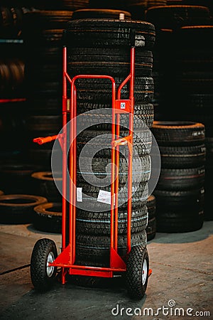 Wheel tyres on the hand truck cart in the warehouse, vertical Editorial Stock Photo