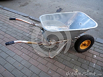 wheelbarrow is on the cobblestones. Construction accessory. Tool for transporting sand and cement. Construction and repair work Stock Photo